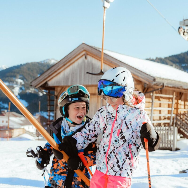 Zwei Kinder lassen sich vom Schlepplift im Familienskigebiet Golzentipp in Obertilliach auf den Berg ziehen.