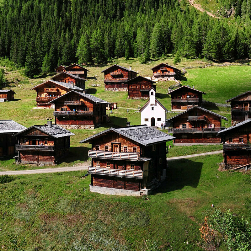 Das Almhüttendorf "Oberstaller Almen" in Innervillgraten im sommerlichen Gebirge mit kleiner Kapelle im Zentrum.