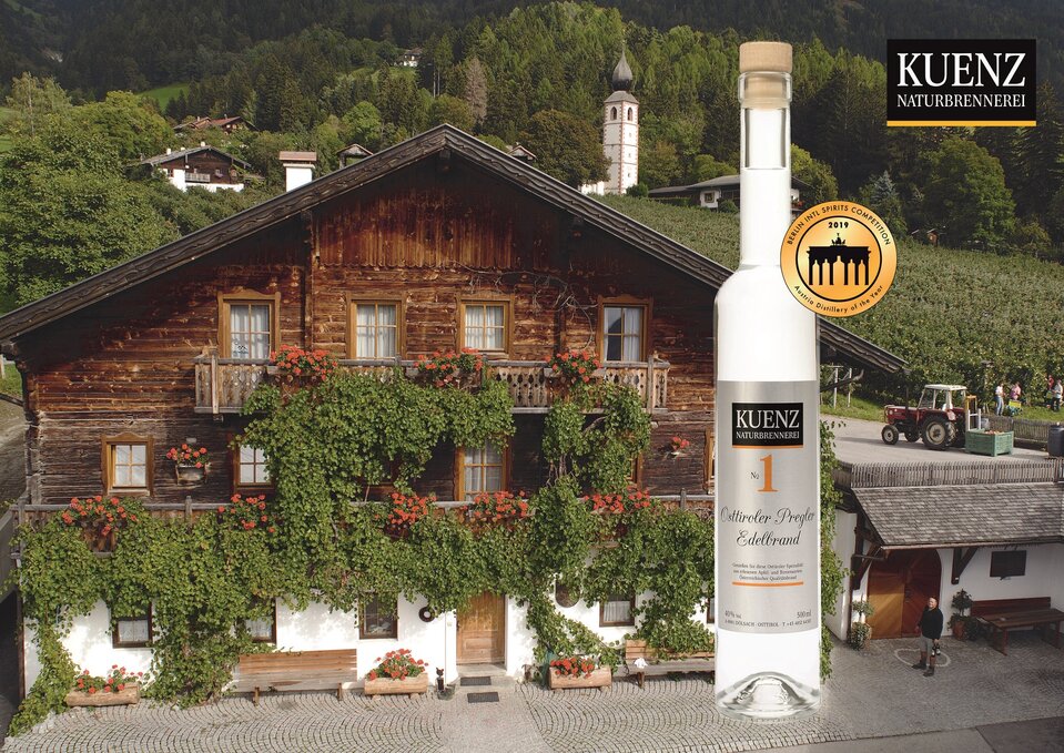 Sommerliche Außenansicht des Kuenzhofes in Dölsach und einer Pregler-Flasche.