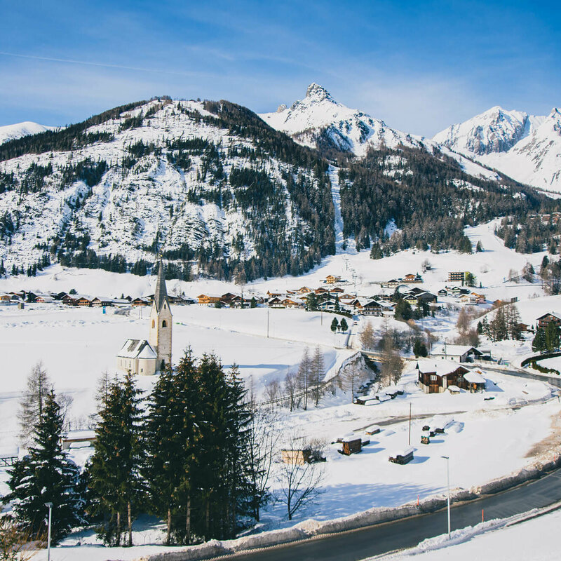 Blick auf das verschneite Kals mit Kirche und Wohnhäusern, an einem sonnigen Tag.