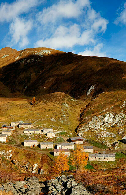 Mehrere alte Gebäuder der Jagdhausalmen stehen sanft eingebettet in herbstlicher Osttiroler Landschaft.