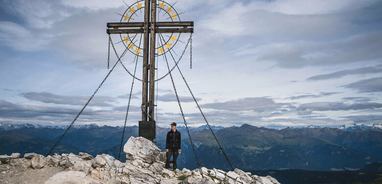 Ein Wanderer am Gipfelkreuz des Berges Große Kinigat.