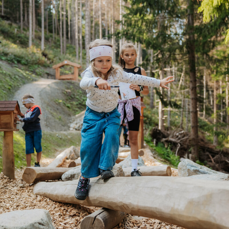 Ein Mädchen balanciert im Wichtelpark über eine hölzerne Konstruktion.