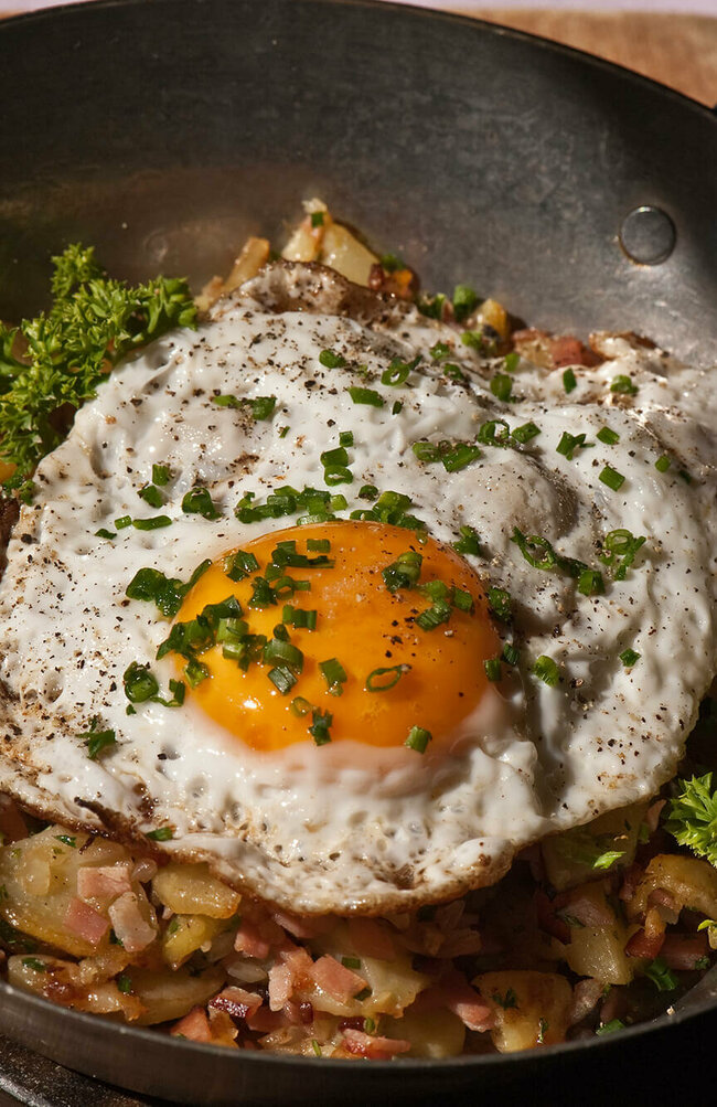 Tiroler Gröstl mit Spiegelei und Schnittlauch in einer kleine Eisenpfanne.