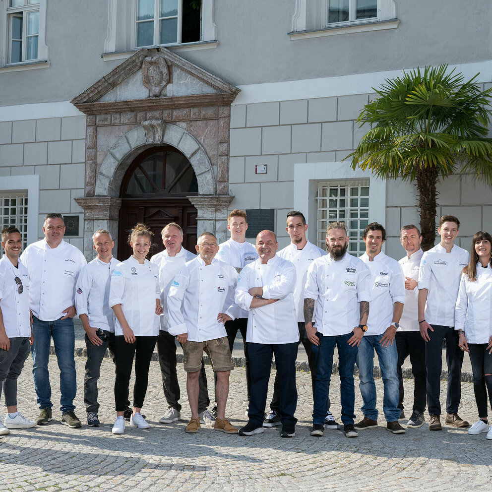 Osttirol de Luxe Köche in einer Reihe aufgefädelt mit weißen Kochjacken und dunklen Hosen vor der Liebburg in Lienz.