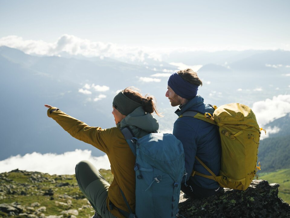 Ein Paar mit Rucksäcken genießt die Aussicht am Bösen Weibele. Die Frau zeigt dem Mann etwas in der Ferne.