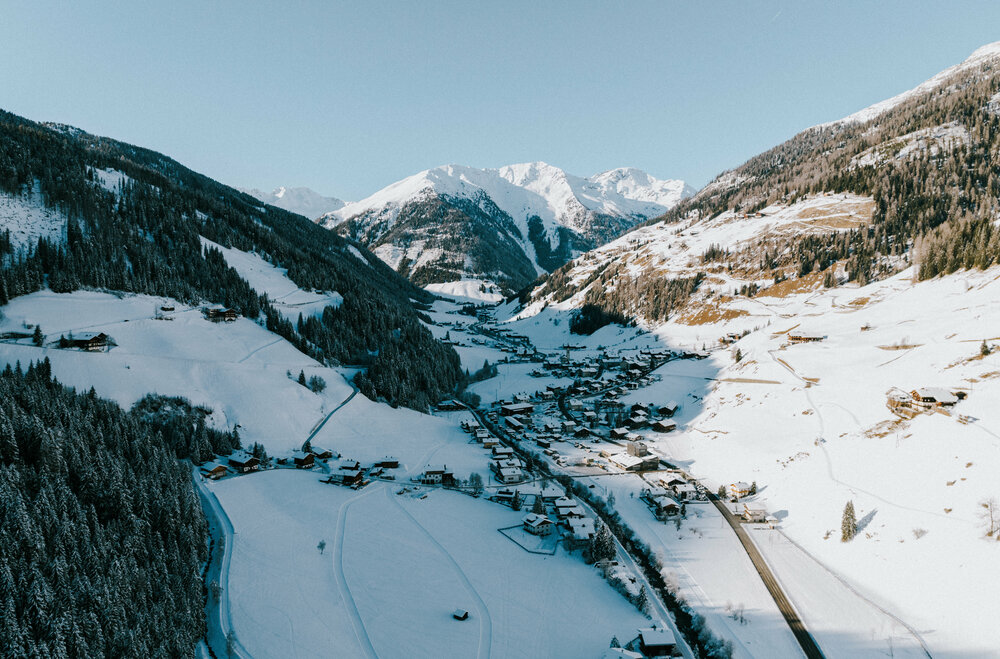 Luftaufnahme von dem mit Schnee bedeckten Dorf Innervillgraten an einem traumhaften Wintertag.