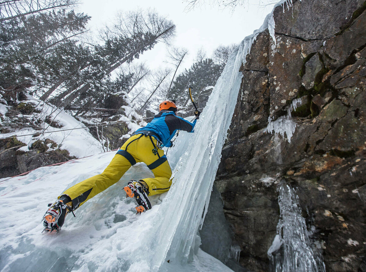 Eiskletterer klettert auf einem zugefrorenen Wasserfall senkrecht nach oben