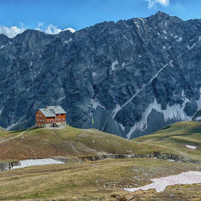 Blick auf die Neue Reichenbergerhütte vor einem Felsmassiv mit letzten Schneeresten.