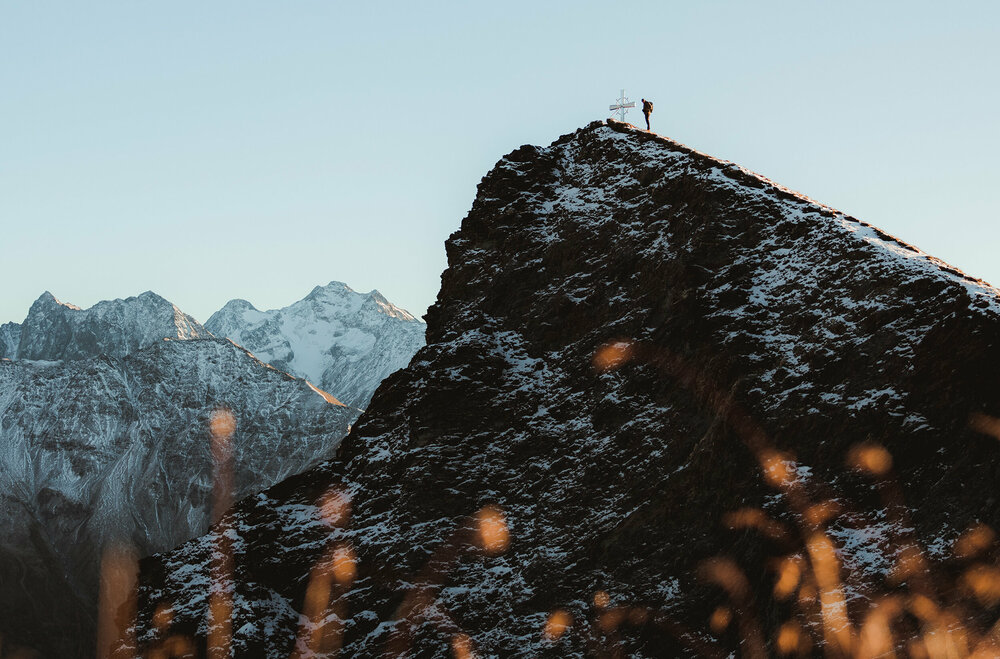 Wanderer am Gipfel des Figerhorns im Herbst mit schon einigen Schneefeldern auf den Bergen.