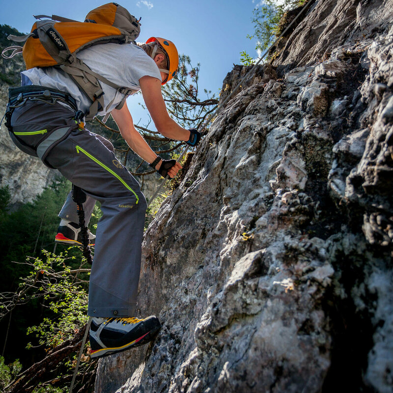 Nahaufnahme von einem Mann mit orangenem Helm und Rucksack auf dem Klettersteig Dopamin in der Galitzenklamm in Osttirol.