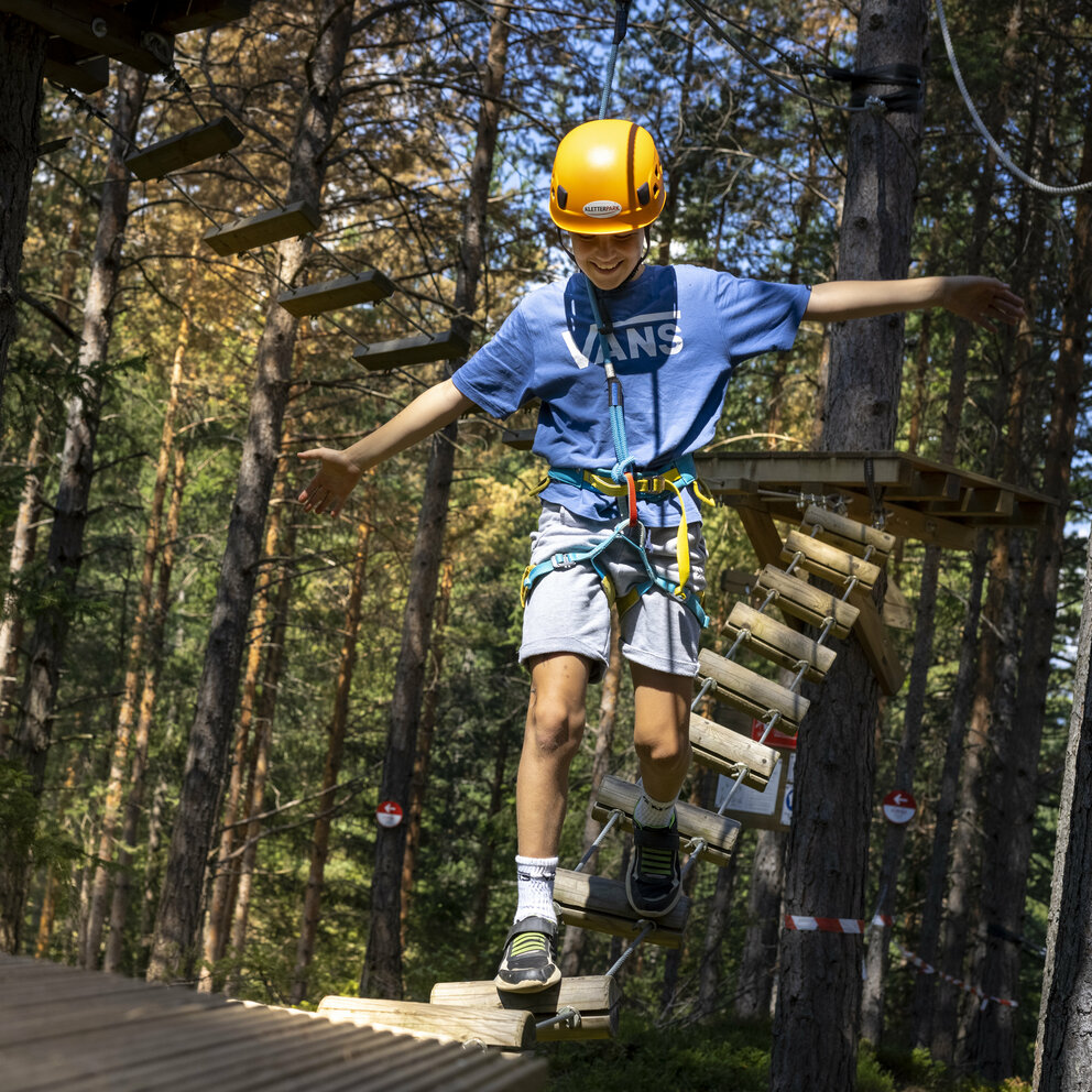 Ein junger Kletterer zeigt seine Geschicklichkeit im Kletterpark Moosalm in Lienz in Osttirol.