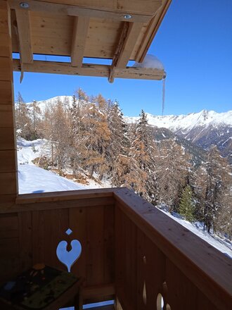 Ein Balkon mit Holzdetails und einem Blick auf schneebedeckte Berge.