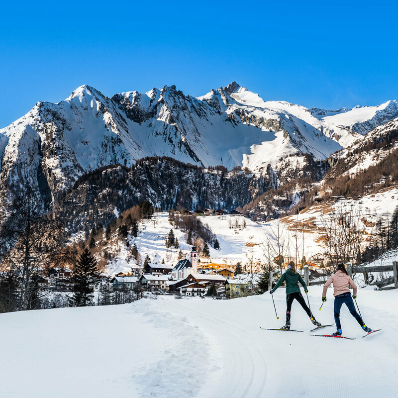 Dorfblick beim Langlaufen in Prägraten mit einer mächtigen Bergkulisse im Hintergrund