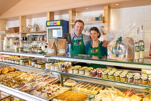Frau und Mann hinter der Theke eines Verkauf von verschiedensten regionalen Produkten.