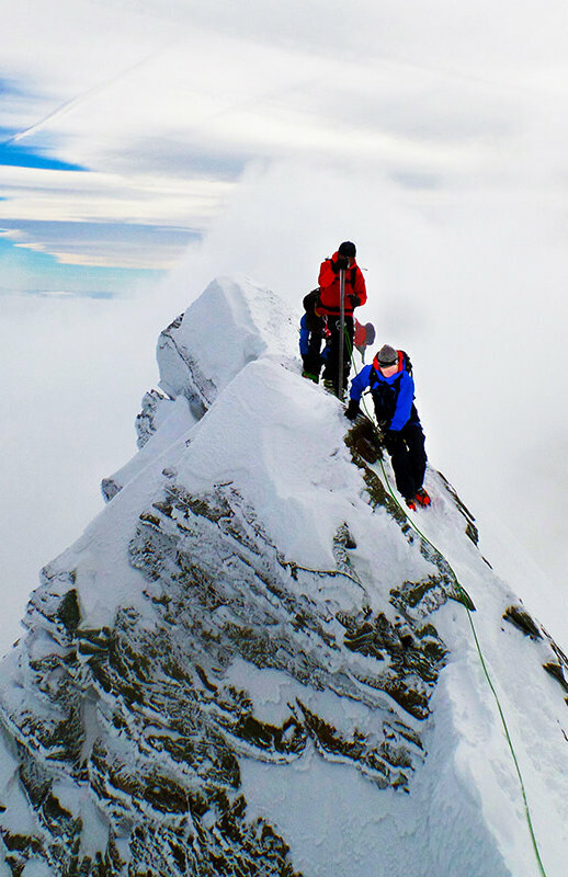Zwei Bergsteiger:innen erklimmen den Gipfle des Kleinglockner