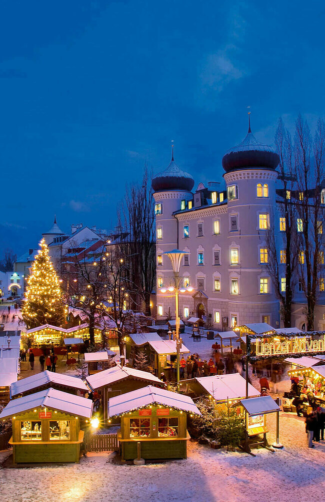 Beleuchteter Adventmarkt am Hauptplatz in Lienz in frühabendlicher Stimmung.