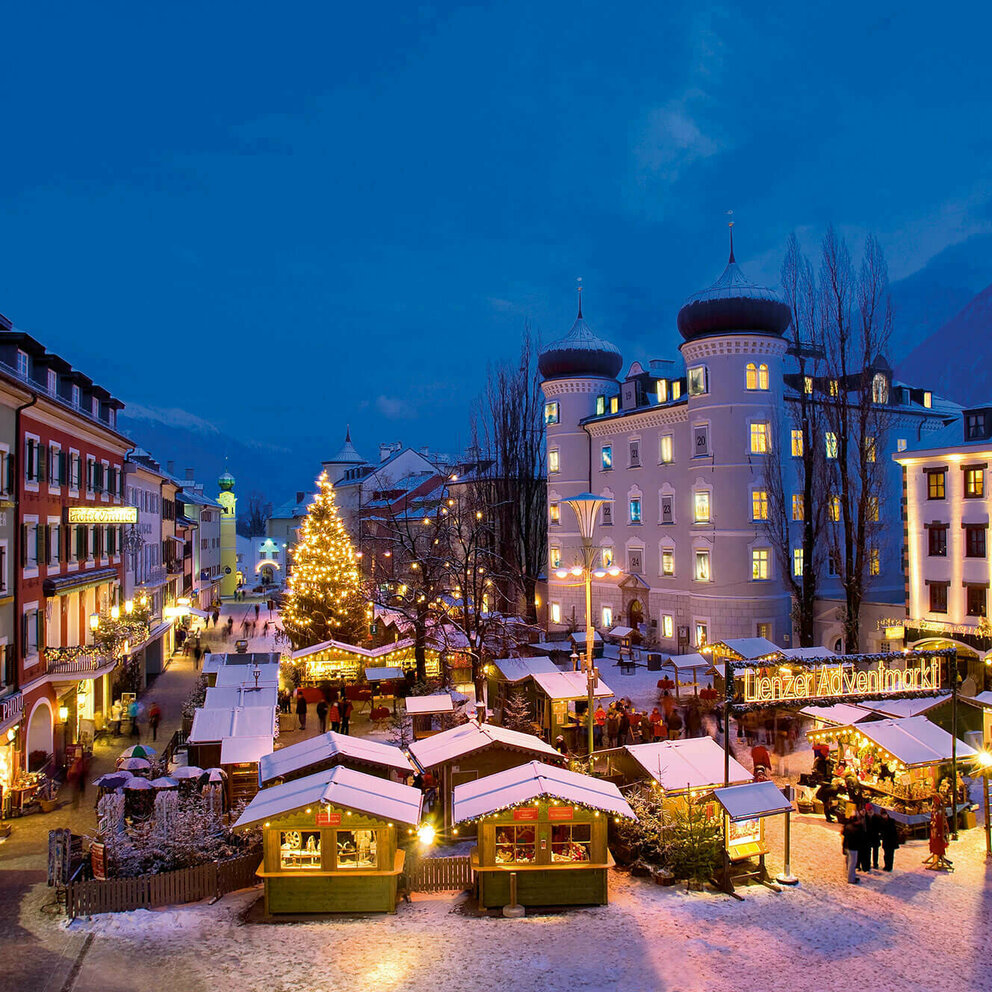 Beleuchteter Adventmarkt am Hauptplatz in Lienz in frühabendlicher Stimmung.