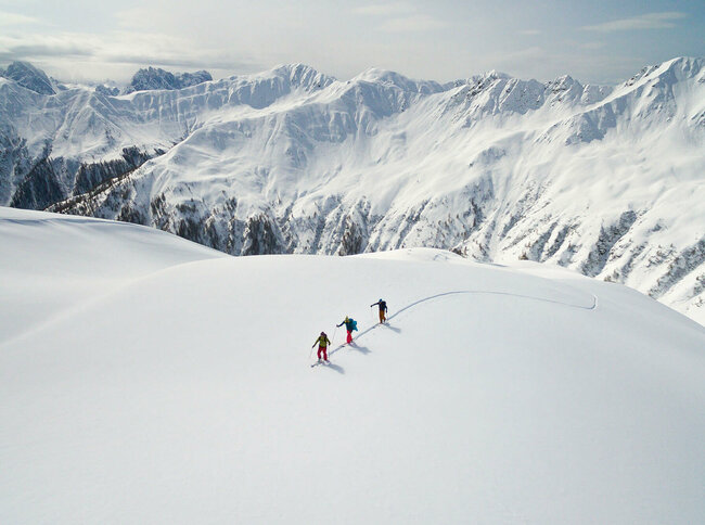 Drei Personen auf Skitour in einer unberührten Schneelandschaft in Herzassvillgraten zum Kalkstein.