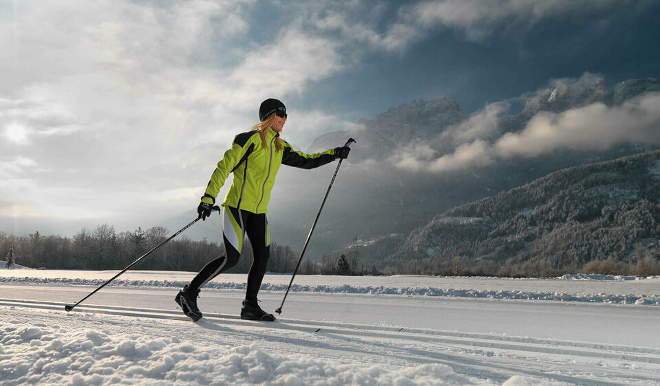 Eine Langläuferin in grün-schwarzem Outfit genießt die perfekten Bedingungen der Langlaufloipe im Lienzer Talboden.