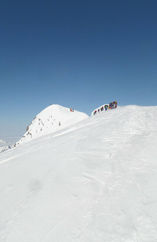 Die letzten Meter vor dem Gipfel des Großvenedigers. Auf dem schneebedeckten Bergrücken stehen einige Bergsteiger.