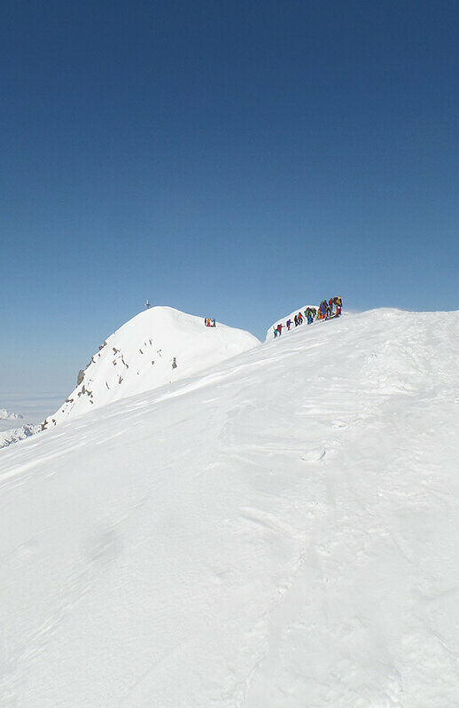 Die letzten Meter vor dem Gipfel des Großvenedigers. Auf dem schneebedeckten Bergrücken stehen einige Bergsteiger.