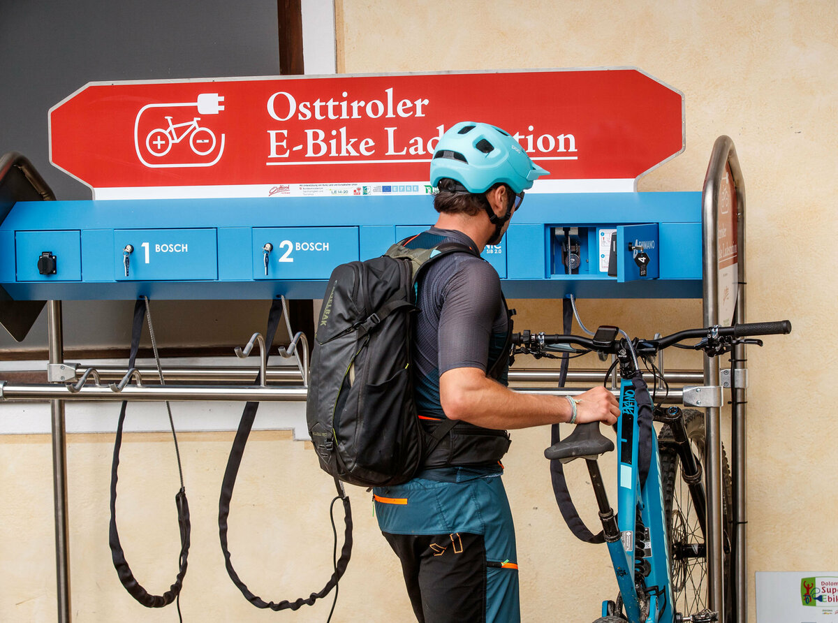 Ein E-Biker lädt sein Bike an der Ladestation Compedalrunde im Kristeinertal im Villgratental in Osttirol.