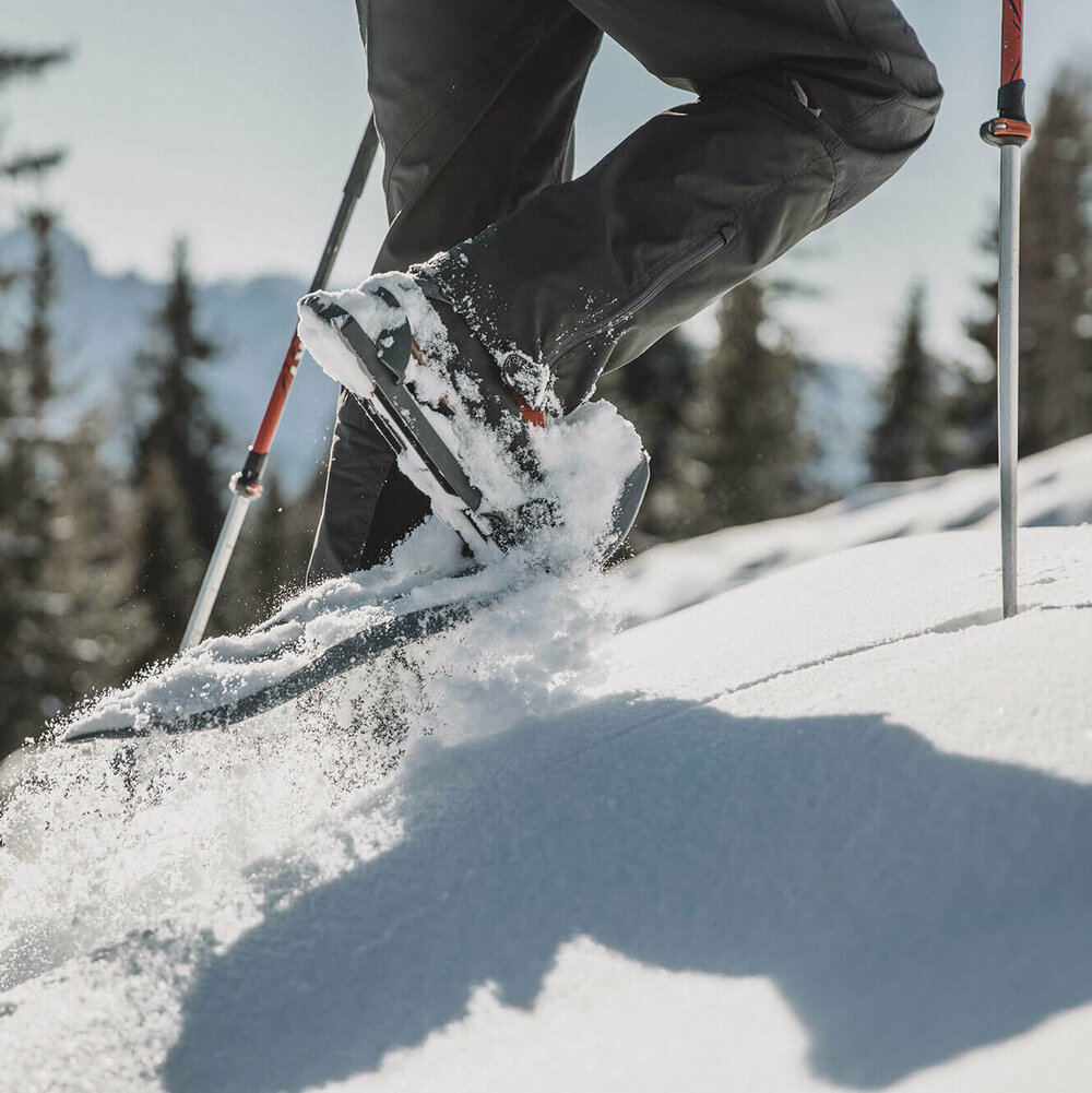 Die Beine eines Mannes beim Schneeschuhwandern durch den Tiefschnee.