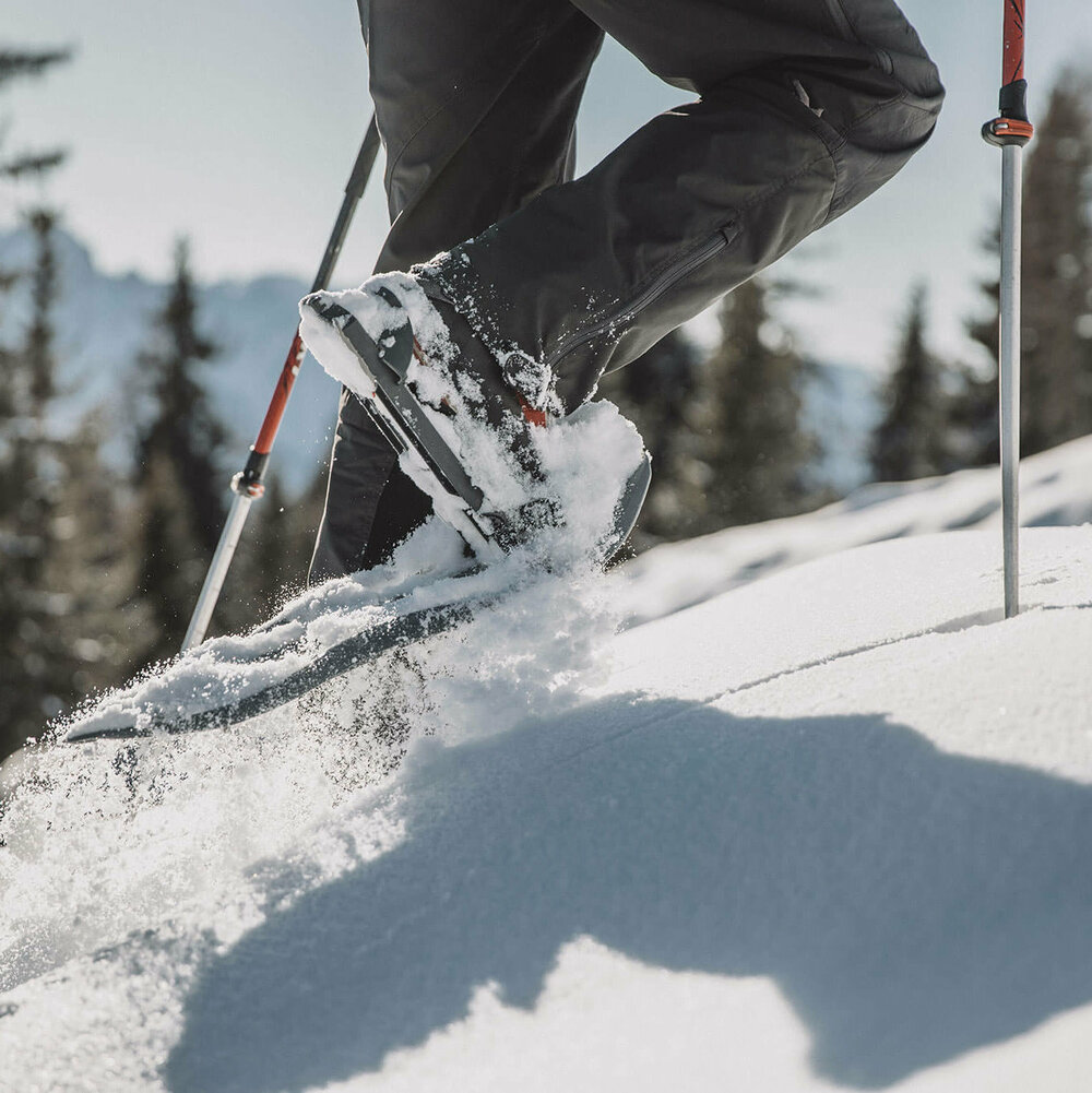 Die Beine eines Mannes beim Schneeschuhwandern durch den Tiefschnee.