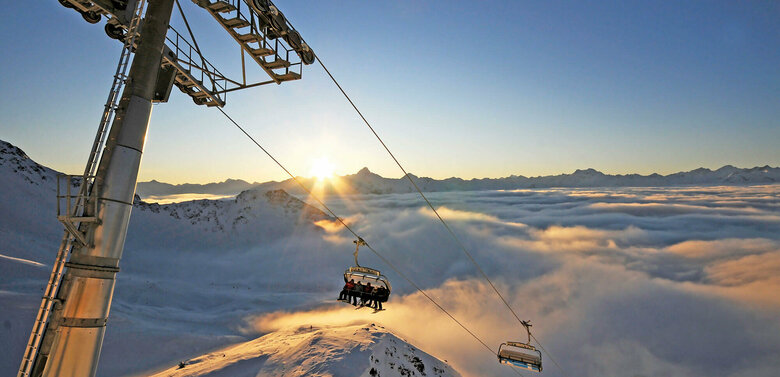 Der Sessellift im Sonnenuntergang im Großglockner Resort Kals Matrei über schneebedeckten Bergen.