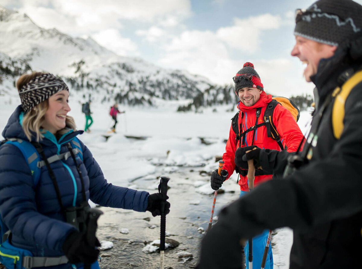 Schneeschuhwanderer:innen machen Rast bei der Wanderung und unterhalten sich.