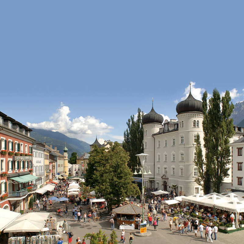 Blick von oben auf den Hauptplatz Lienz mit einigen Marktständen und Besuchern.