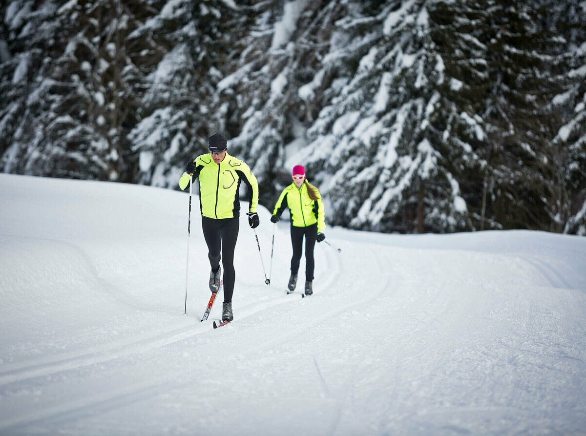 Zwei Langläufer:innen beim Langlaufen auf der Loipe Obertilliach