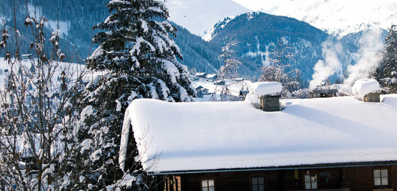 Blick auf eine verschneite, dunkle Holzhütte im Winter im Defereggental.