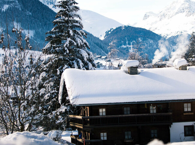 Blick auf eine verschneite, dunkle Holzhütte im Winter im Defereggental.
