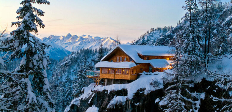 Die Dolomitenhütte auf einem Felsen in den Lienzer Dolomiten im Winter in der Dämmerung.