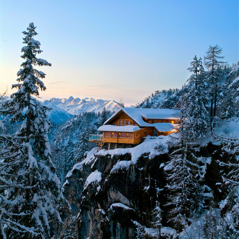 Die Dolomitenhütte auf einem Felsen in den Lienzer Dolomiten im Winter in der Dämmerung.