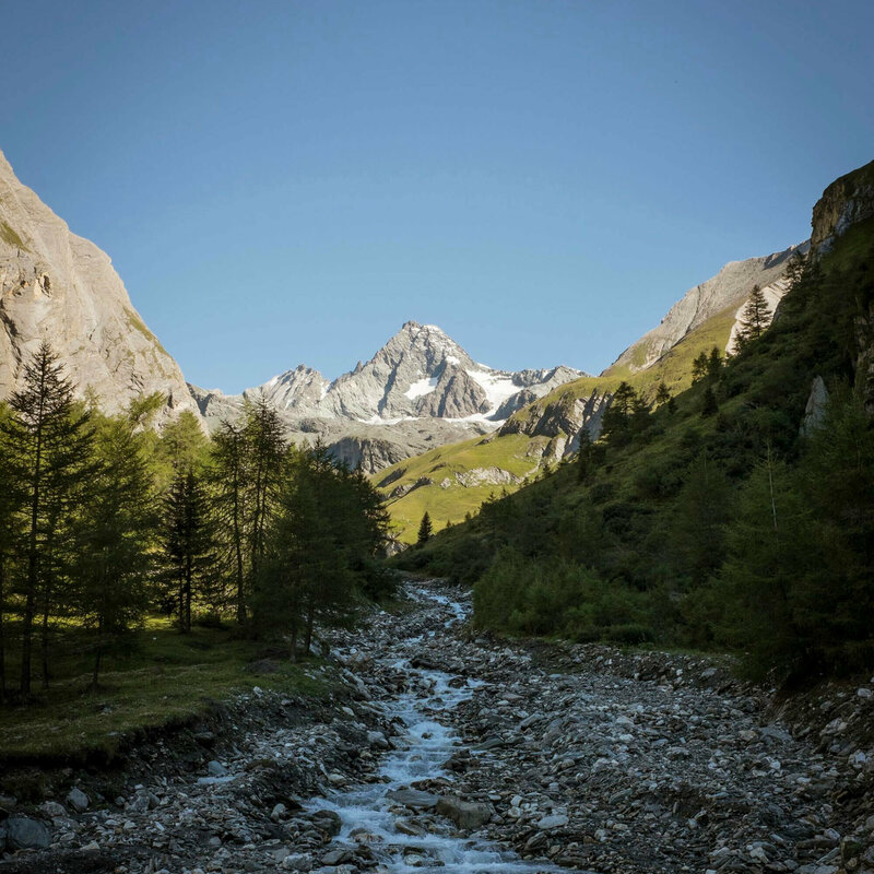 Blick auf einen kleinen Bach mit Grossglockner im Hintergrund an einem herrlichen Tag mit blauem Himmel.