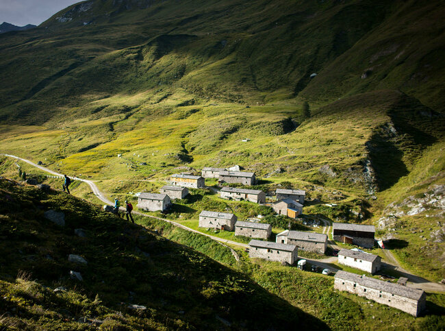 Mehrere alte Gebäude der Jagdhausalmen stehen sanft eingebettet in Osttiroler Landschaft.