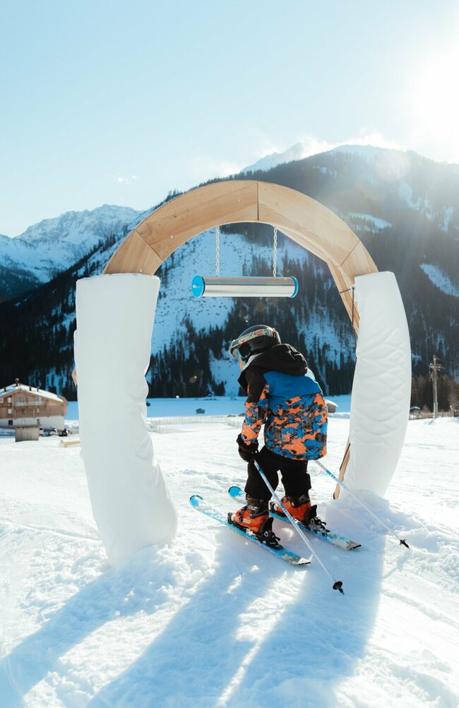 Kleiner Skifahrer fährt durch Bogen im Kinderland Obertilliach