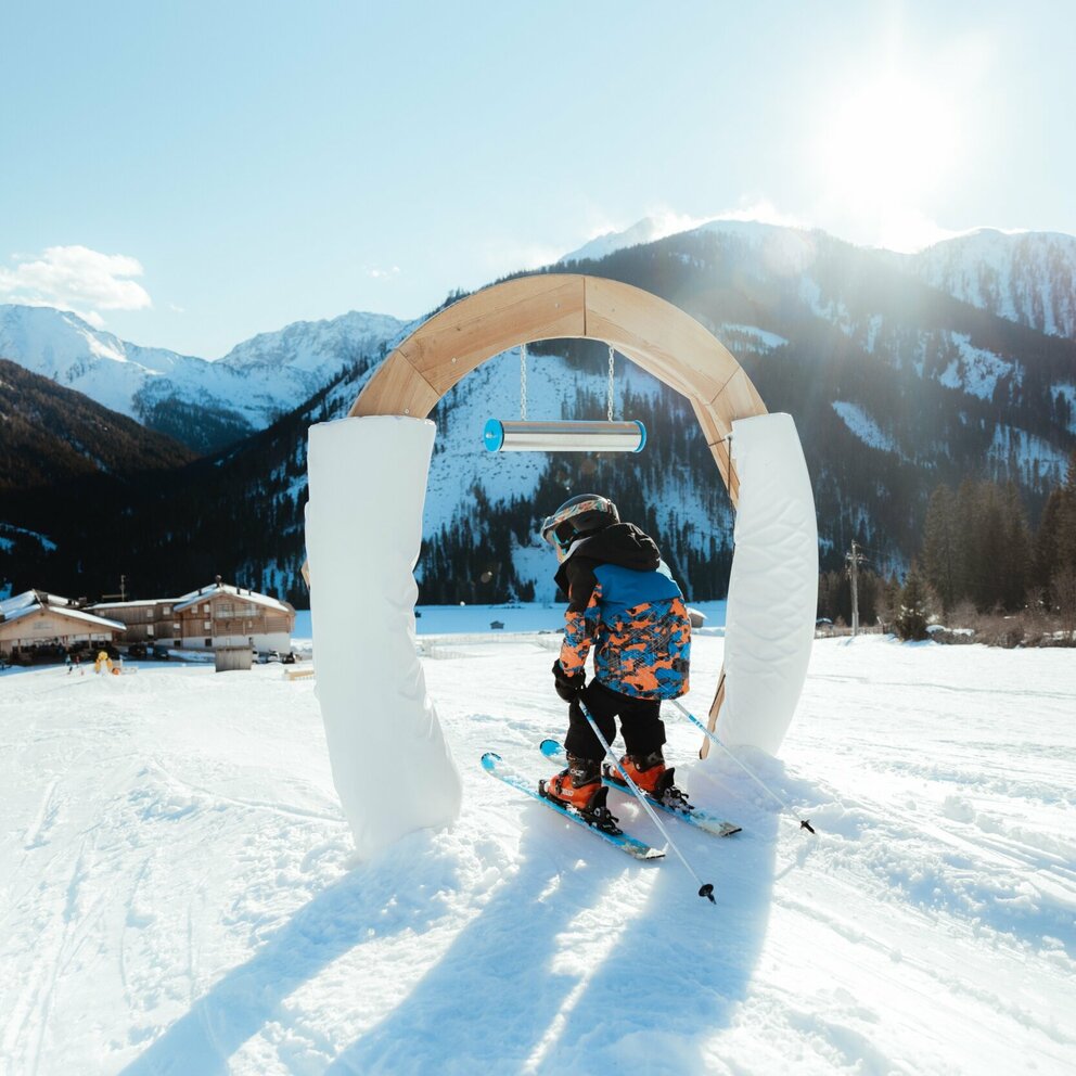 Kleiner Skifahrer führt durch Bogen im Kinderland in Obertilliach