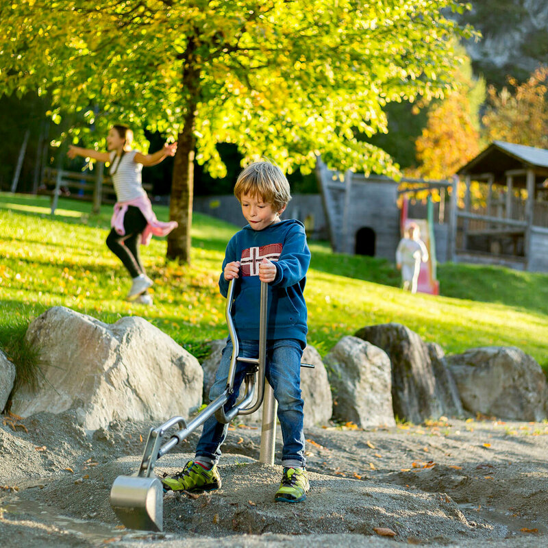 Ein Junge sitzt auf einem Spielgerät auf dem Spielplatz in der Galitzenklamm.