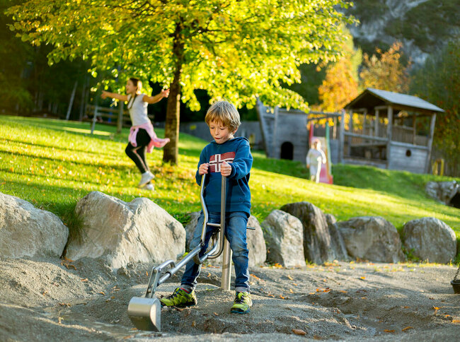 Ein Junge sitzt auf einem Spielgerät auf dem Spielplatz in der Galitzenklamm.