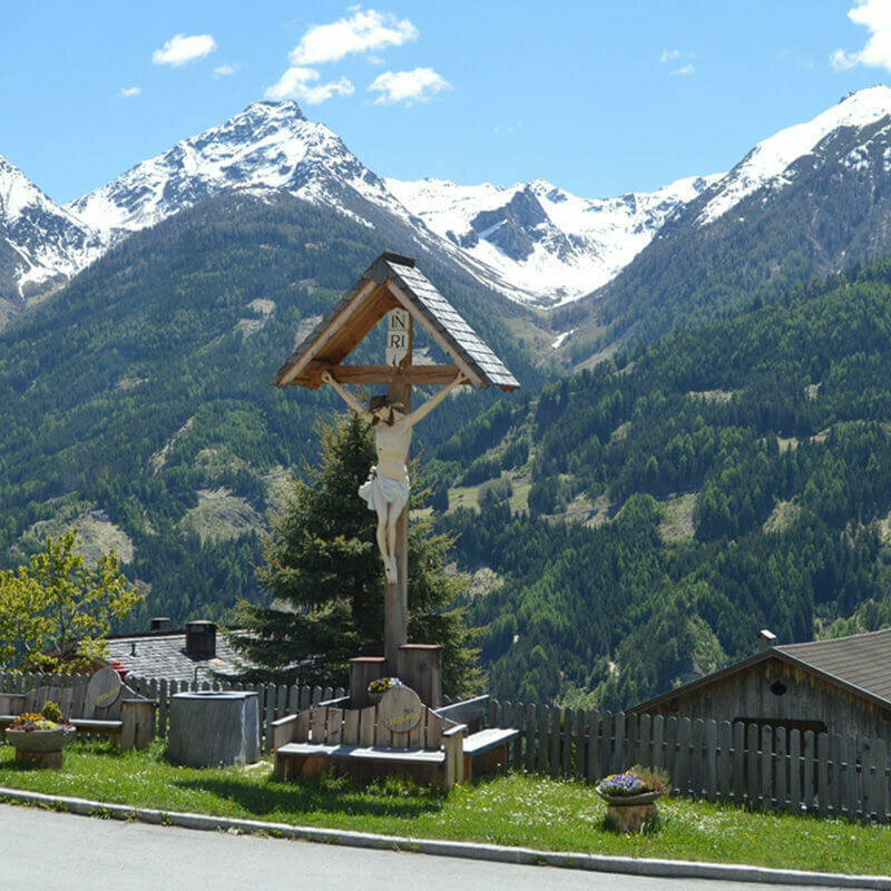 Ein Bildstöckl am Straßenrand auf dem Virgentaler Sonnseitenweg. Im Hintergrund liegt noch Schnee auf den Berggipfeln.