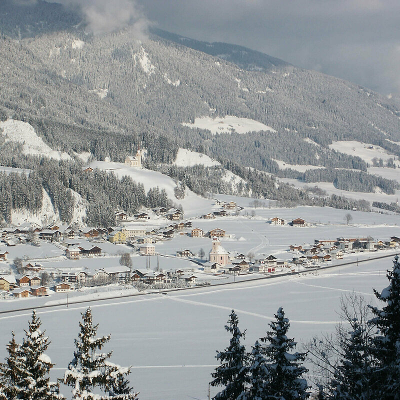 Aufnahme des Ortes Strassen von oben in winterlicher Umgebung und frisch verschneite Wäldern.