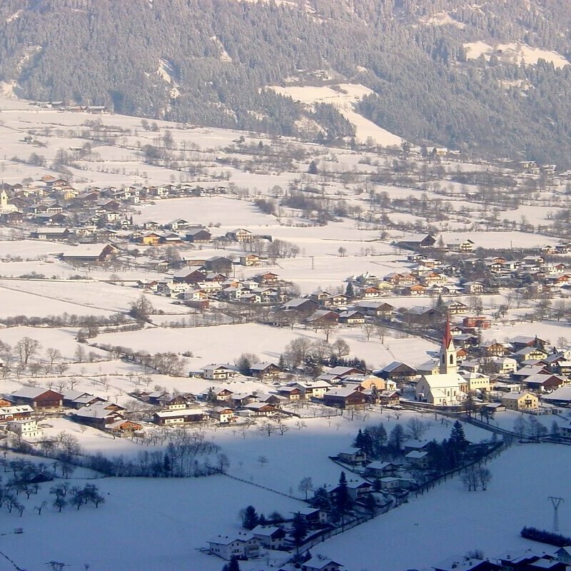 Blick auf Oberlienz im Winter. Das Dorf ist mit Schnee bedeckt.