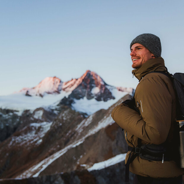 Wanderer nach Sonnenuntergang am Figerhorn mit dem schneebedeckten Großglockner im Hintergrund.