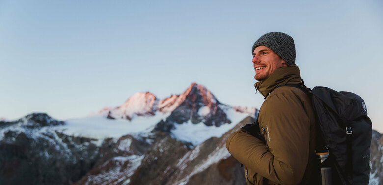 Wanderer nach Sonnenuntergang am Figerhorn mit dem schneebedeckten Großglockner im Hintergrund.