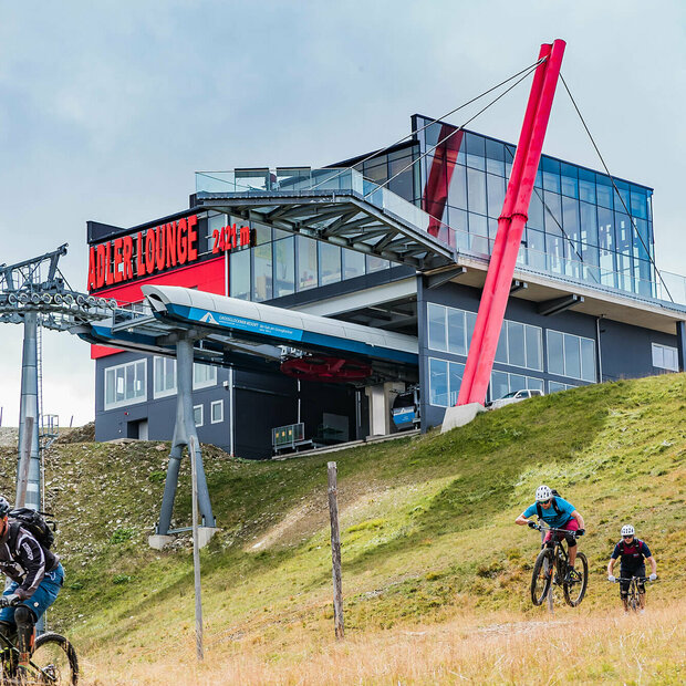 Zwei talwärts fahrende Mountainbiker unterhalb der Bergstation der Gondelbahn im Großglockner Resort Kals-Matrei