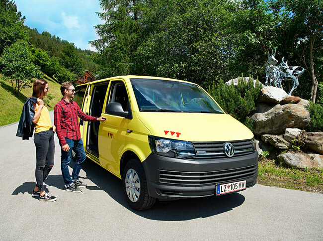 Auf dem Bus sind zwei Wanderer zu sehen, die gerade in das gelbe Wanderbus einsteigen
